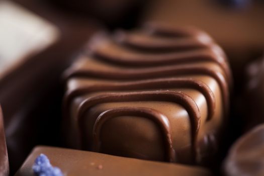 Chocolate bars and pralines on wooden background