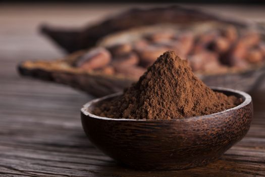 Cocoa beans in the dry cocoa pod fruit on wooden background