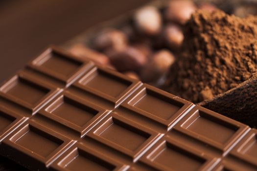 Chocolate bar, candy sweet, cacao beans and powder on wooden background