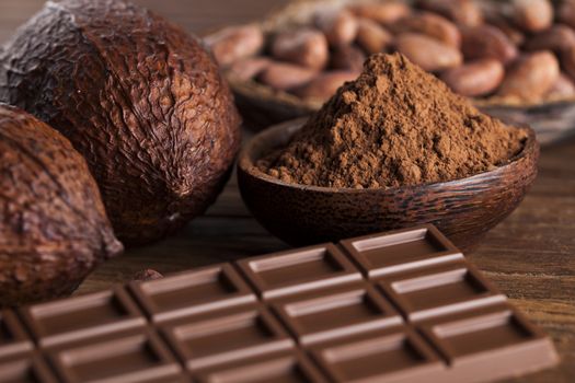 Chocolate bar, candy sweet, cacao beans and powder on wooden background