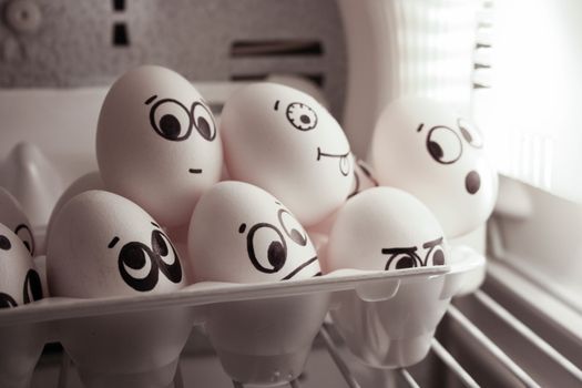 The concept of surveillance and eavesdropping. Face eggs are funny in the fridge. Photo for your design. The egg peeps