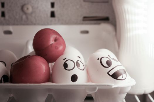 Concept of surprise. Eggs in the refrigerator near the lamp with a plum. Photo for your design.