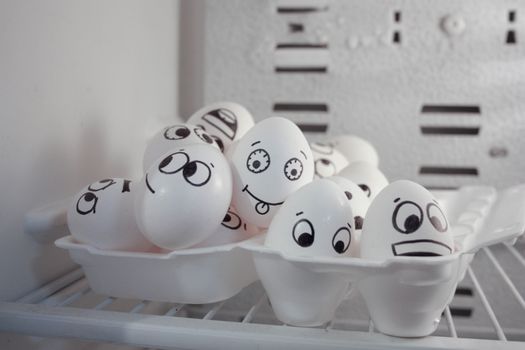 Overpopulation concept. Funny eggs. Photo for your design. Eggs in a container in the refrigerator. Eggs look at each other and lie on top of each other.