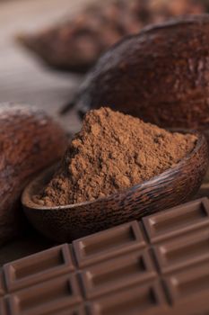 Chocolate bar, candy sweet, cacao beans and powder on wooden background