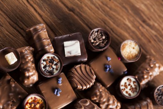 Chocolate bars and pralines on wooden background