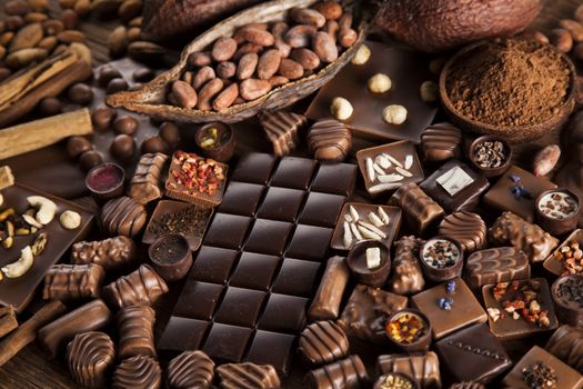 Chocolate bars and pralines on wooden background