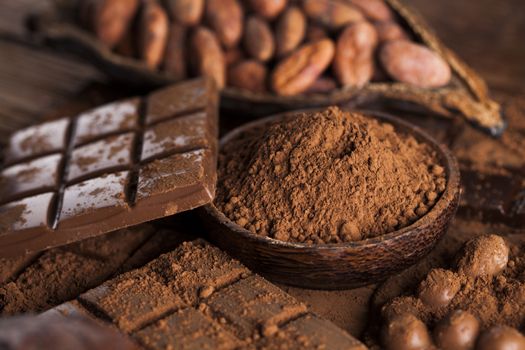 Dark homemade chocolate bars and cocoa pod on wooden