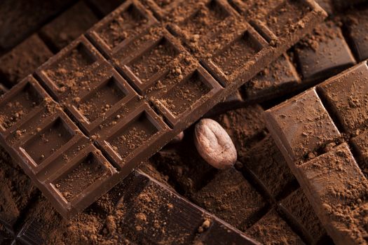 Dark homemade chocolate bars and cocoa pod on wooden