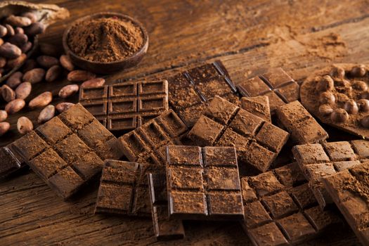 Dark homemade chocolate bars and cocoa pod on wooden