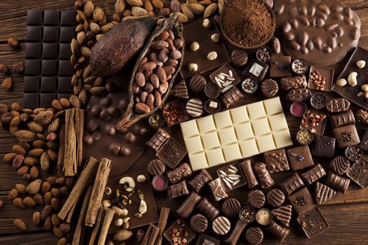 Chocolate bars and pralines on wooden background