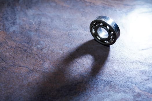 One ball bearing on dark background with long shadow