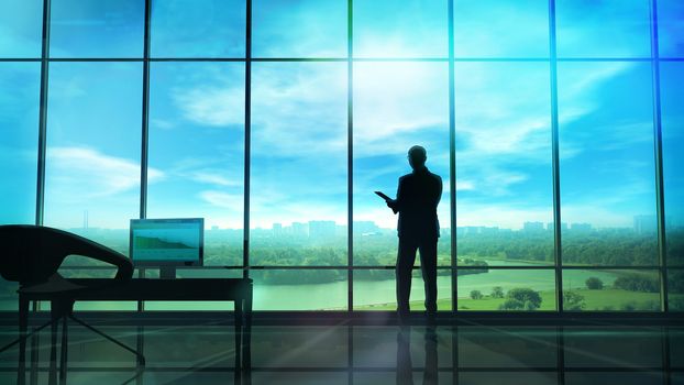 Silhouette of a man in a huge office in front of large windows.