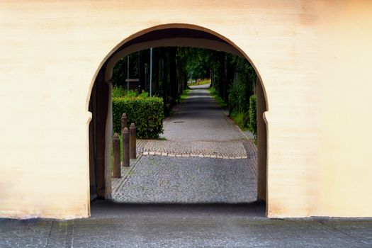 Gate of a historical farmstead behind a narrow road.