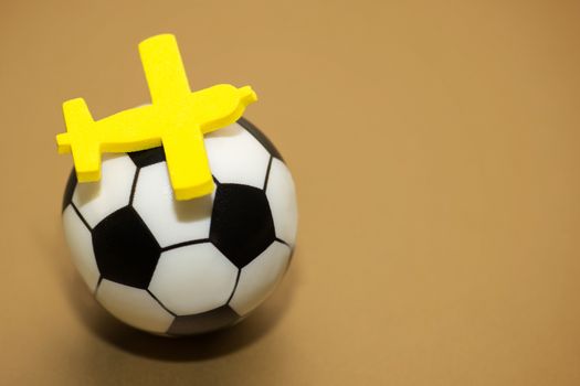 Yellow toy airplane on a soccer ball. The concept of flying to the football championship.
