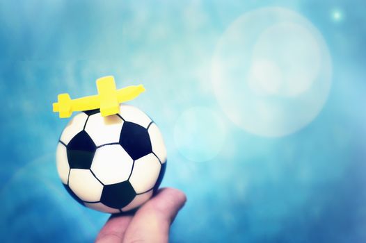 Yellow toy airplane on a soccer ball. The concept of flying to the football championship.