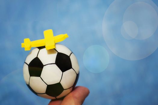 Yellow toy airplane on a soccer ball. The concept of flying to the football championship.