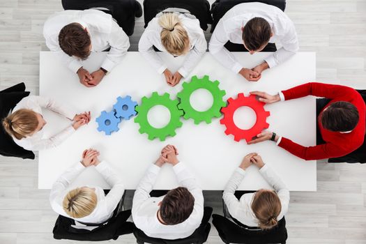 Business problem solution, mechanism of business, teamwork concept, business team sitting around white table with cogs