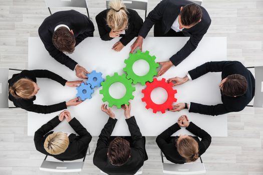 Business problem solution, mechanism of business, teamwork concept, business team sitting around white table with cogs