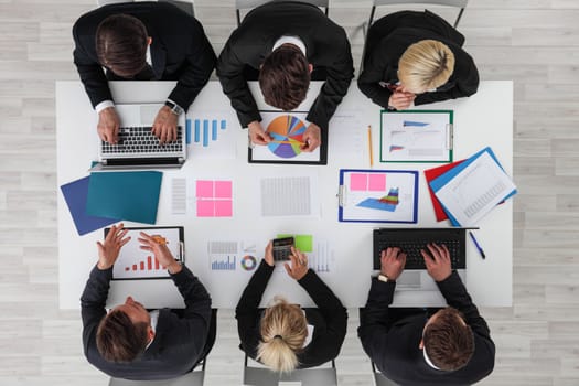Business people work with statistics documents with tables and diagrams sitting around the table