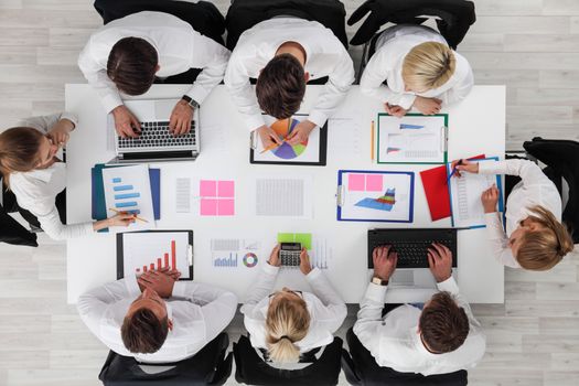 Business people work with statistics documents with tables and diagrams sitting around the table