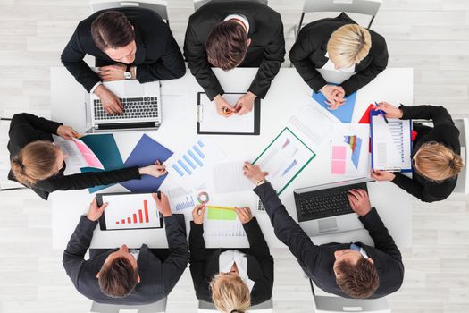 Business people work with statistics documents with tables and diagrams sitting around the table
