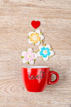 colorful artificial flower with red cup on wooden background.