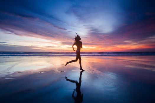 Woman in bikini running on the beach at sunset. Bali island, Indonesia
