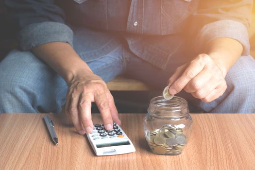 Saving money concept and hand putting money coin in the glass jar for financial and accounting concept.