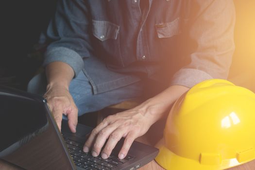 Architect engineer using laptop for working with yellow helmet and laptop on table.
