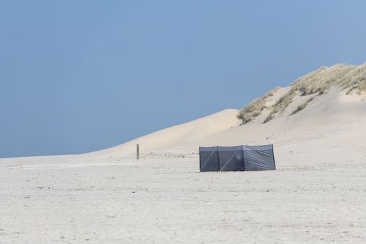 Wind screen on the beach with dunes on the background

