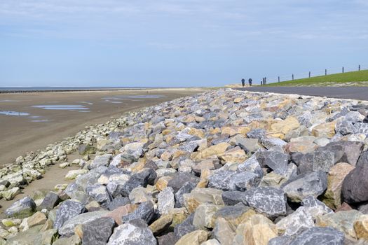 Wadden Sea dike with large colorful natural stone pebbles and cycle path from the island Ameland in northern Netherlands bordering the UNESCO protected Wadden Sea
