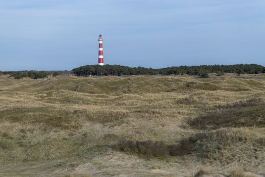 Lighthouse of the island Ameland in northern Netherlands with dunes on the foreground
