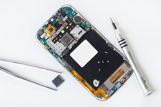 disassembled mobile phone and tools on white background