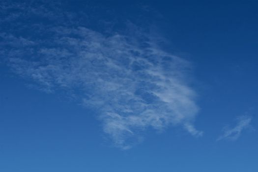 Clear blue sky with plain white cloud with space for text background. The vast blue sky and clouds