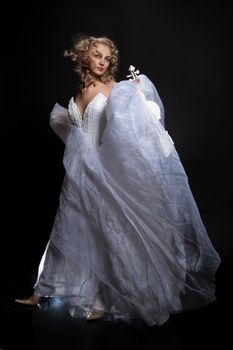 Young attractive woman in a wedding dress with a white violin on a studio background