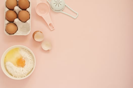 Ingredients and kitchen bake tools for cooking cake or sweets - eggs, flour on a pastel punchy pink background. Top view of a holiday baking still life.