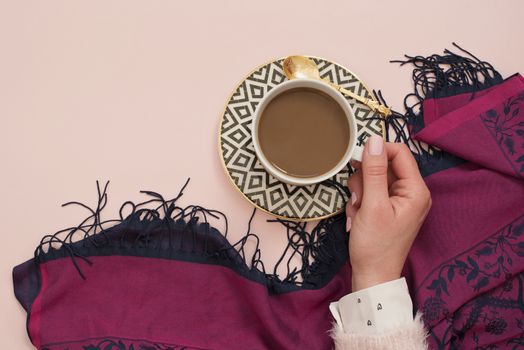 Women hand holding coffee. Latte in a white, black and gold coffee cup. Feminine workplace concept. Freelance fashion comfortable femininity workspace with coffee. Bright pink and purple background.