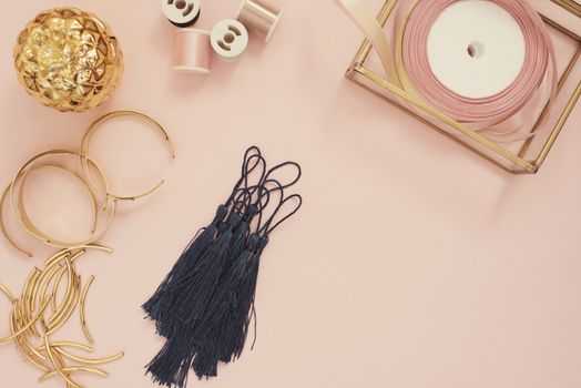 Jewelry designer workplace. Handmade, craft concept. Materials for making jewelry ? golden scissors, ribbons, gold tubes, bracelet settings, tassels. Freelance workspace in flat lay style. 