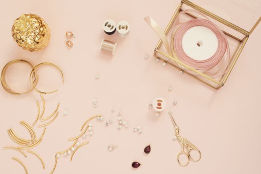 Jewelry designer workplace. Handmade, craft concept. Materials for making jewelry ? golden scissors, ribbons, gold tubes, bracelet settings. Freelance workspace in flat lay style.