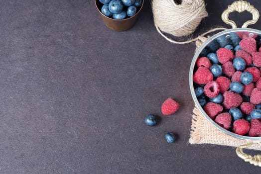 Fresh raspberries and blueberries dark picture with copy space on left. Fresh fruits, berries in an old copper cup, bowl. Dark Styled Stock Photo, Black Background