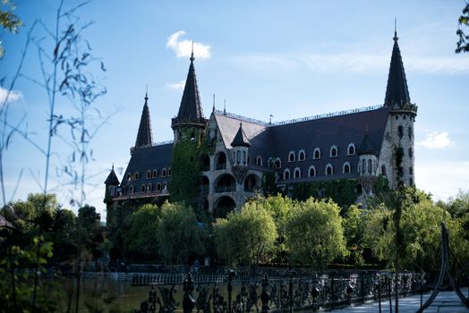 Beautiful old fairy-tale castle near Burgas, Bulgaria. Walls of the castle, green flower garden and wonderful lake with swans and wrought iron fence