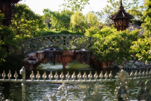 Beautiful bridge over the lake in green park. Beautiful pond and footbridges surrounded with trees and flowers.