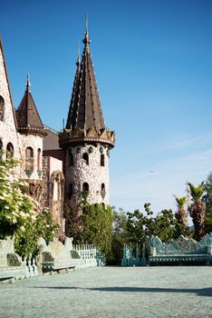 Beautiful old fairy-tale castle near Burgas, Bulgaria. Walls of the castle, green flower garden. Stone walkway. Alley in beautiful garden with flowers and trees around. Summer in the garden