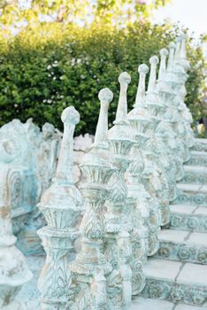 Close of railing of old baroque stairs, outdoors. Stairs made of stone, Alley in beautiful garden with flowers and trees around.