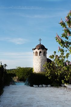 Old stone chapel in the garden of fabulous ancient castle. Alley in beautiful garden with flowers and trees around. Summer in the garden