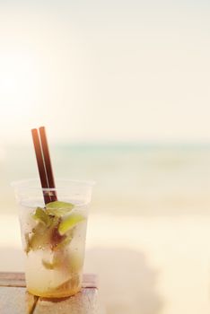 Mojito cocktail on the beach, blurred beach background. Sun, sun haze, glare