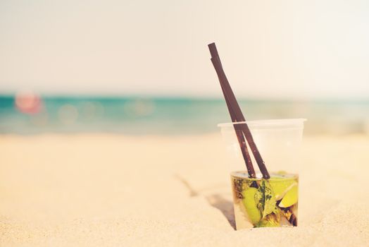 Mojito cocktail on the beach, blurred beach background. Sun, sun haze, glare