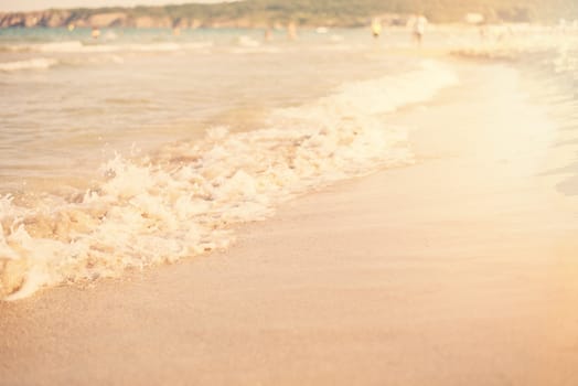 Sand and wave background. Soft wave of the turquoise sea on the sandy beach. Natural summer beach background with copy space. Sun, sun haze, glare