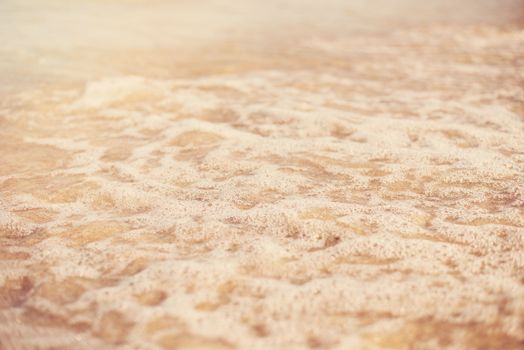 Sand and wave background. Soft wave of the turquoise sea on the sandy beach. Natural summer beach background with copy space. Sun, sun haze, glare