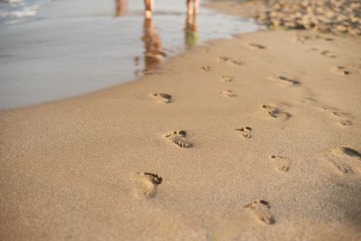 Footprints in the sand. Human footprints leading away from the viewer. A row of footprints in the sand on a beach in the summertime. Summer Vacation